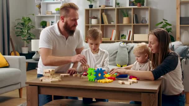 Familia feliz jugando con juguetes sobre la mesa en la sala de estar — Vídeos de Stock