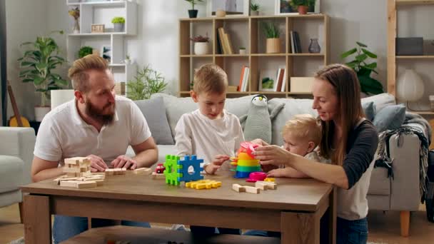 Szczęśliwa rodzina bawi się zabawkami na stole w salonie — Wideo stockowe