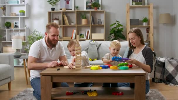 Familia feliz jugando con juguetes sobre la mesa en la sala de estar — Vídeos de Stock