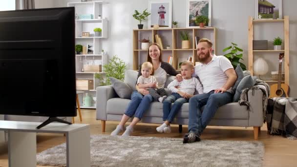 Familie schaut fern, während sie auf einer Couch im Wohnzimmer sitzt — Stockvideo