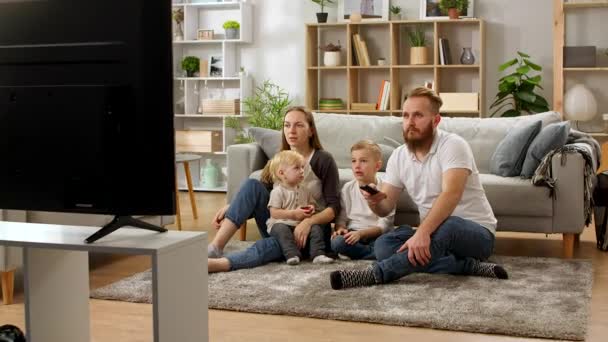 Family watching tv while sitting on the living room floor — Stock Video