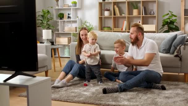 Familia viendo dibujos animados en la televisión y cantando canciones — Vídeo de stock