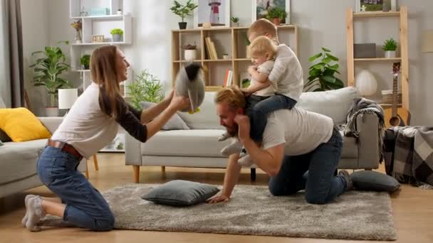 Ung pappa kryper på golvet med söta små barn söner på ryggen — Stockvideo