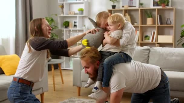 Joven papá arrastrándose en el suelo llevando lindo niño pequeño hijos en la espalda — Vídeos de Stock