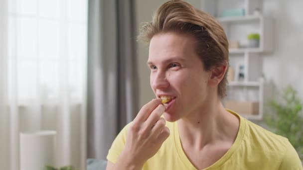 Смішний молодий чоловік кусає картоплю фрі — стокове відео
