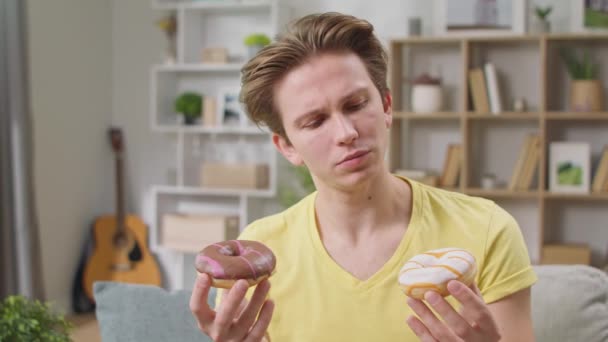 Chico alegre elige cuál de los dos donuts para comer — Vídeos de Stock