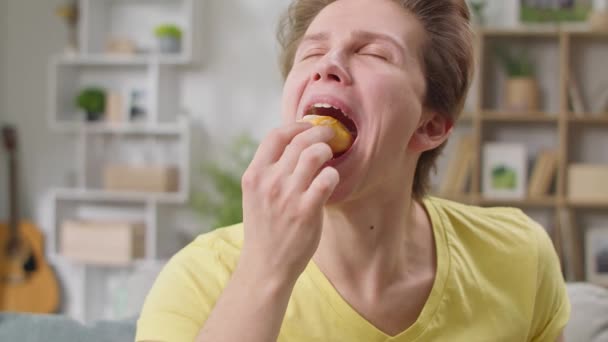 Веселий хлопець їсть пончик і лиже пальці — стокове відео