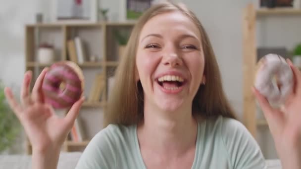 Radosna dziewczyna wybiera, który z dwóch pączków do jedzenia — Wideo stockowe