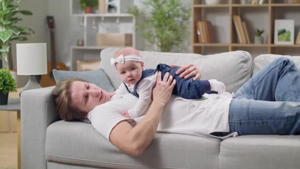 Dad kisses little daughter lying not on the couch — Stock Video