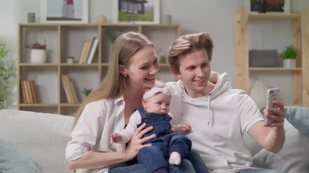 Giovane famiglia che si fa un selfie sul divano in soggiorno — Video Stock