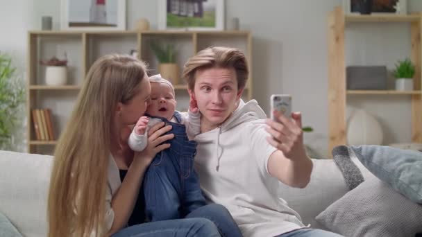 Giovane famiglia che si fa un selfie sul divano in soggiorno — Video Stock
