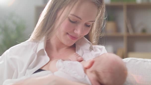 Mam geeft borstvoeding aan haar dochtertje in de ochtendzon in de woonkamer — Stockvideo