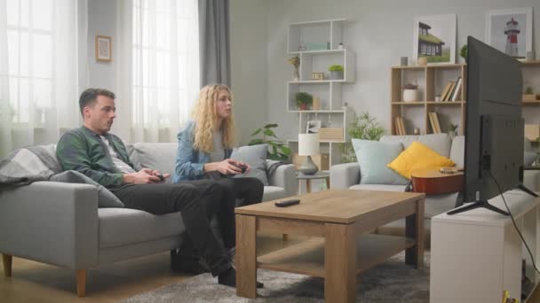 Jongeman en vrouw spelen op een spelcomputer met gamepads in hun handen — Stockvideo