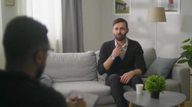 Genç sakallı bir adam psikanalistle seansta.