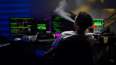 Medium shot of a young hacker smoking a cigarette before returning to work