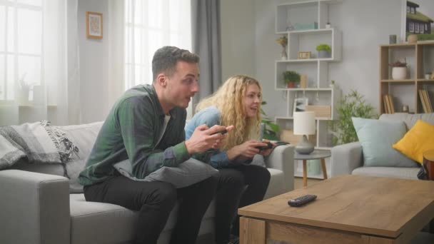 Par som spelar en spelkonsol med gamepads i händerna — Stockvideo