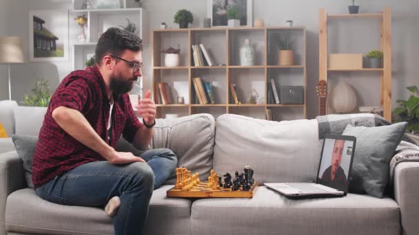 Двое молодых людей играют в шахматы дома в карантине в изоляции с помощью видеозвонка . — стоковое видео