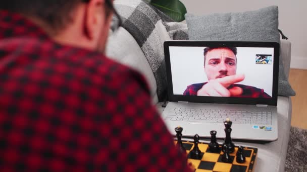 Twee jonge mannen spelen thuis in quarantaine in afzondering schaken met behulp van een videogesprek. — Stockvideo