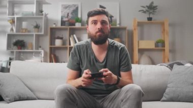 Genç adam Coronavirus salgını sırasında evde video oyunu oynuyor.