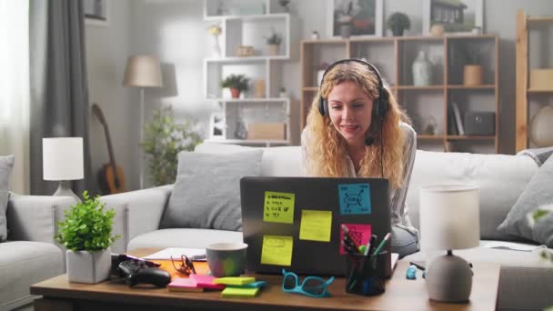 Een jonge vrouw begint thuis te werken, begroet een klant via videogesprekken — Stockvideo