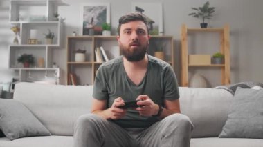 Koronavirüs salgını sırasında evde tek başına video oyunu oynayan bir adam.
