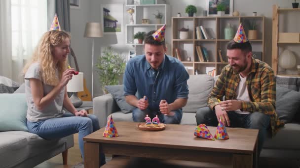 Tres amigos celebran un cumpleaños. Soplando las velas . — Vídeos de Stock
