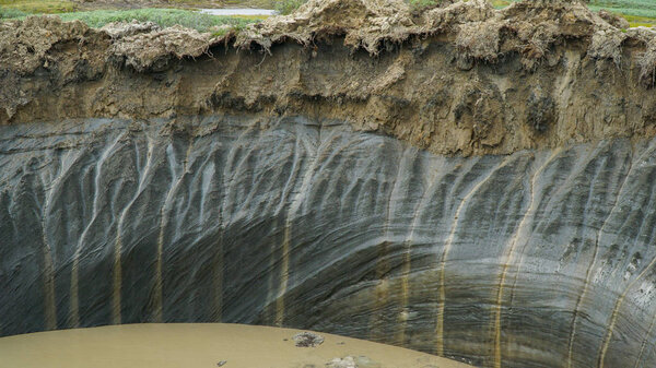 YAMAL PENINSULA, RUSSIA - JUNE 18, 2015: Expedition to the giant funnel of unknown origin. The crater wall from the permafrost.