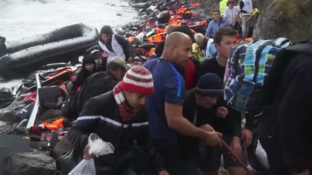 Lesbos, Řecko - 5. listopadu 2015: Uprchlíky opustit gumovém člunu u skalnatého pobřeží. — Stock video