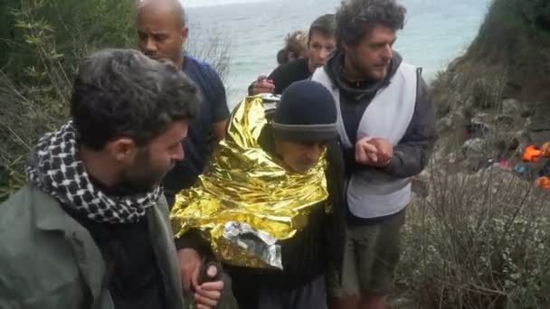 Лесбос, Греція - 5 листопада 2015: Волонтери Довідка старих біженців йти на березі. — стокове відео