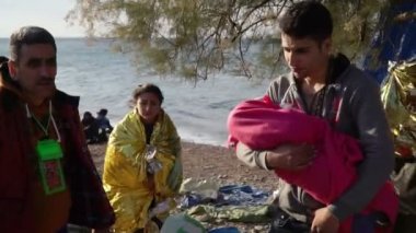 Lesvos, Yunanistan - 5 Kasım 2015: Genç adam sahilde bir bebekle.
