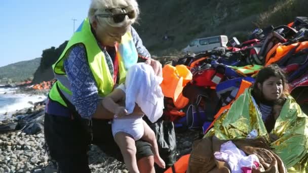 LESVOS, GRECIA - 5 NOV 2015: La voluntaria se quita la ropa mojada de los niños refugiados . — Vídeos de Stock