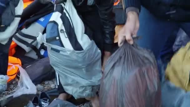 LESVOS, GREECE - NOV 5, 2015: Refugees men on shore pulled backpacks of plastic bags. — Stock Video