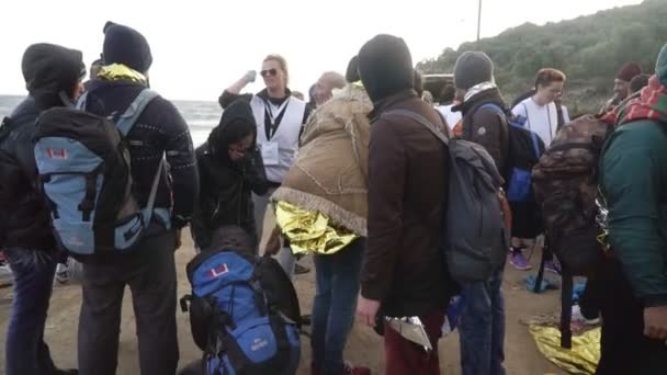 Lesvos, Griekenland - Nov 5, 2015: Vrijwilliger aan vluchtelingen op de oever legt uit welke weg te gaan. — Stockvideo