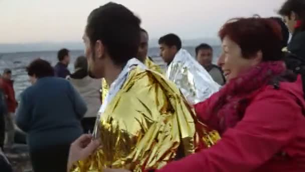 LESVOS, GRECIA - NOV 5, 2015: I volontari danno ai rifugiati una pellicola calda per riscaldarsi. Everning . — Video Stock