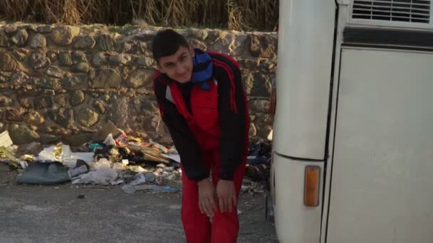 LESVOS, GRÉCIA - NOV 5, 2015: Refugiado é aquecido perto do tubo de escape do ônibus . — Vídeo de Stock
