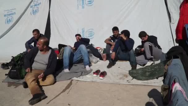 LESVOS, GREECE - NOV 5, 2015: Refugee men in the camp sit on the pavement. — Stock Video