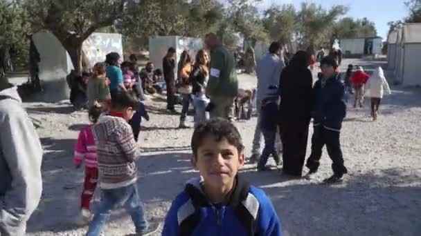 Lesvos, Grekland - 5 Nov 2015: Skara människor i flyktinglägret. Boy titt på kameran. — Stockvideo