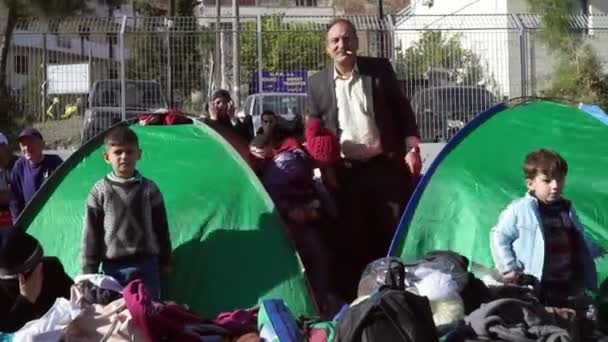 Lesvos, Griekenland - Nov 5, 2015: Vluchtelingen in tenten in de haven van Mytilene zijn hand zwaaien naar de camera. — Stockvideo