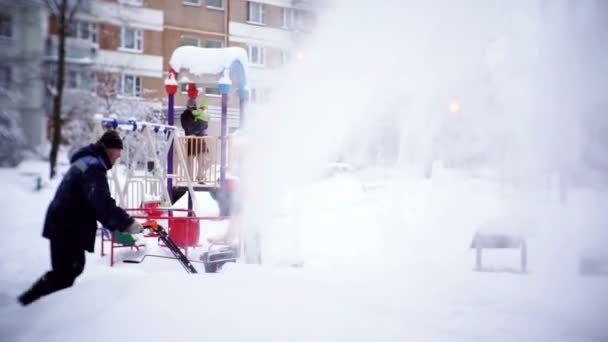 Прибиральник прибирає доріжку зі снігом у дворі багатоквартирного будинку . — стокове відео
