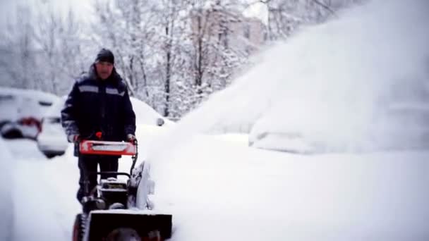 The janitor clears the track with a snowplow in the courtyard of an apartment building. — Stock Video