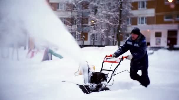 Woźny czyści na torze snowplow na dziedzińcu budynku mieszkalnego. — Wideo stockowe