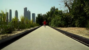 Komik küçük çocuk çalışır ve parkta trambolin yolda atlar. BAE, Sharjah, Al Noor Adası - Bahçe kelebek.