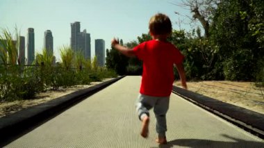 Komik küçük çocuk çalışır ve parkta trambolin yolda atlar. BAE, Sharjah, Al Noor Adası - Bahçe kelebek.