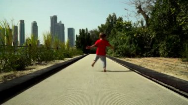 Komik küçük çocuk çalışır ve parkta trambolin yolda atlar. BAE, Sharjah, Al Noor Adası - Bahçe kelebek.