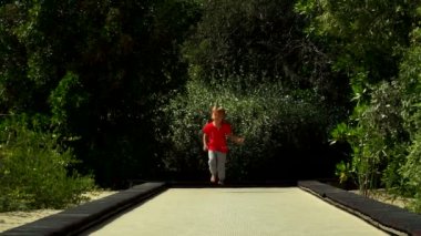 Komik küçük çocuk çalışır ve parkta trambolin yolda atlar. BAE, Sharjah, Al Noor Adası - Bahçe kelebek.