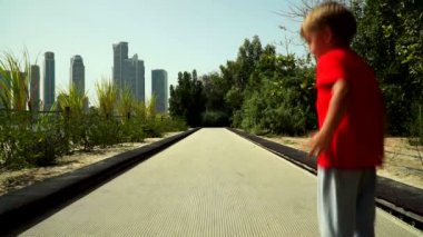 Komik küçük çocuk anne ile çalışır ve parkta trambolin yolda atlar. Al Noor Adası - Sharjah, Kelebek Bahçe