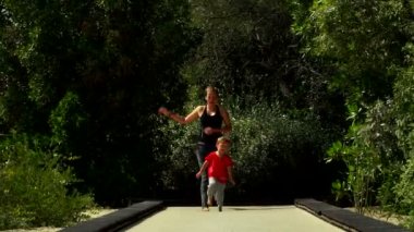 Komik küçük çocuk anne ile çalışır ve parkta trambolin yolda atlar. Al Noor Adası - Sharjah, Kelebek Bahçe