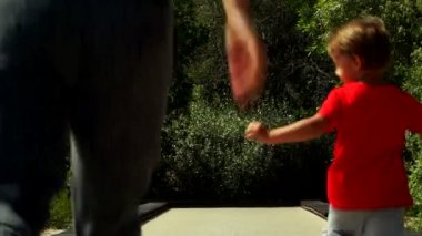 Komik küçük çocuk anne ile çalışır ve parkta trambolin yolda atlar. Al Noor Adası - Sharjah, Kelebek Bahçe