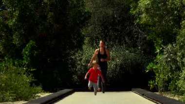 Komik küçük çocuk anne ile çalışır ve parkta trambolin yolda atlar. Al Noor Adası - Sharjah, Kelebek Bahçe