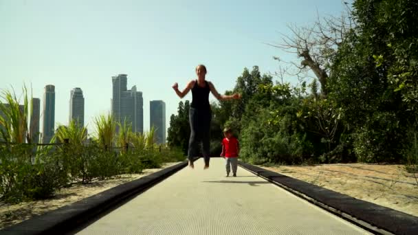 Grappig Jongetje Met Moeder Loopt Springt Trampoline Track Het Park — Stockvideo